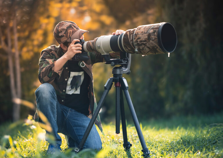 Wildlife Photographer behind the lens and showing a camera on a tripod.